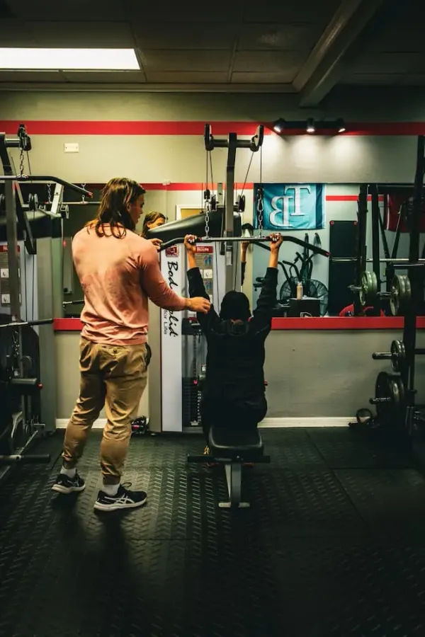 Heroes Fitness coach guiding a client through a lat pulldown